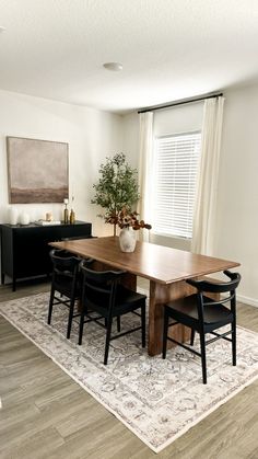 a dining room table with four chairs and a rug on the floor in front of it