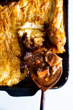 a close up of food in a pan on a table with a spoon next to it