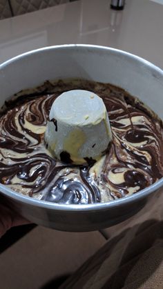 a person holding a metal bowl filled with chocolate and marshmallows in it