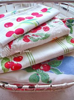 three towels are stacked on top of each other in a basket, with cherries printed on them