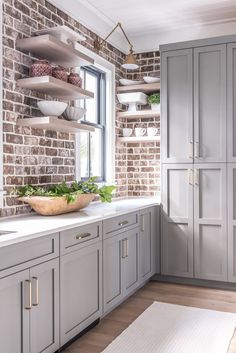 a kitchen with gray cabinets and white counter tops, along with shelves that have plants on them