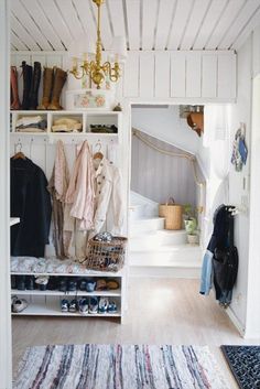 a white closet filled with lots of clothes next to a stair case and rugs