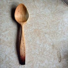 a wooden spoon sitting on top of a counter next to a wallpapered floor