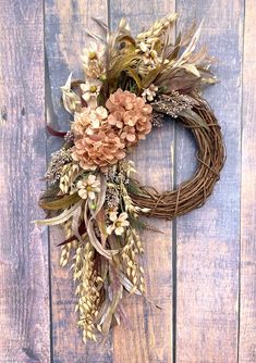 a wreath with dried flowers hanging on a wooden wall