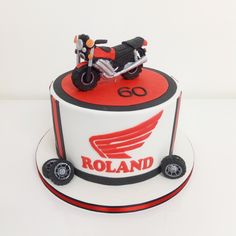 a red and white cake with a motorcycle on the top that says roland in black lettering