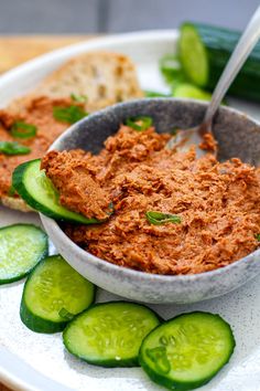 a bowl filled with cucumbers and bread on top of a plate