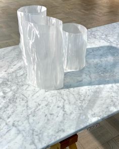 two white vases sitting on top of a marble table