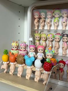 a bunch of toys that are sitting on a shelf in front of some shelves with fruit