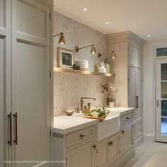 a kitchen with white cabinets and gold faucets on the counter top, along with two sinks