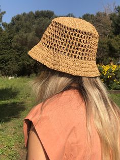 the back of a woman's head wearing a straw hat with crochet