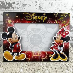 two mickey and minnie mouse magnets are shown in front of a photo frame on a table