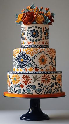 a multi - tiered cake decorated with flowers and leaves on a stand against a gray background