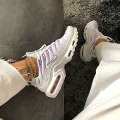 a person wearing white pants and purple sneakers