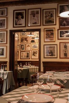 a dining room with pictures on the wall and table cloths set for two people