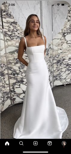 a woman in a white dress standing next to a marble wall