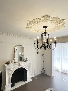 a living room with a fireplace, mirror and chandelier hanging from the ceiling