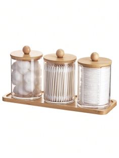 three canisters with wooden lids are sitting on a shelf