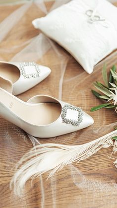 a pair of white shoes sitting on top of a wooden table next to a pillow