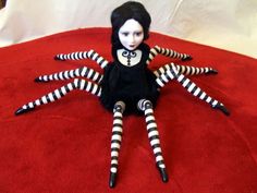 a doll with black and white striped legs sitting on top of a red bed spread