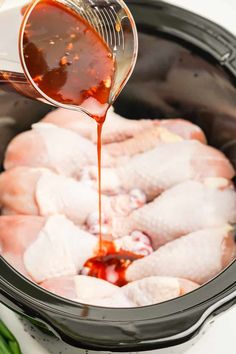 chicken being poured into an air fryer with broth in the middle and green onions on the side