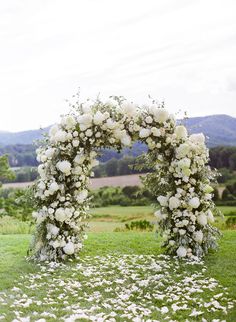 a white floral arch in the middle of a field