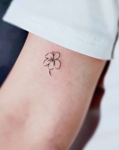 a small four leaf clover tattoo on the left side of the arm