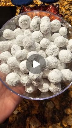 a person holding a bowl full of snowballs on top of a granite countertop