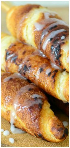 three pastries with icing on them sitting on a cutting board