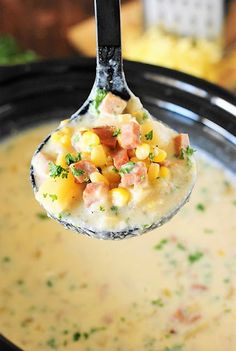 a spoon full of soup with ham and corn