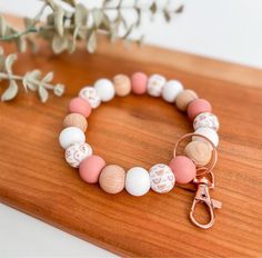 a close up of a bracelet on a wooden surface with a flower in the background