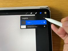 a hand is holding a white pen and pointing to the screen on a tablet computer