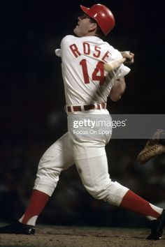 a baseball player is swinging his bat at the ball in front of him and wearing a red helmet