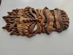 an intricately carved piece of wood is displayed on the wall in front of a white background