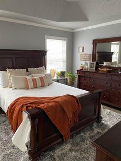 a bedroom with a bed, dresser and mirror