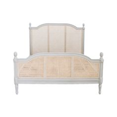 a white bed with wicker headboard and foot board on top of the frame