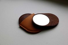 a brown leather coaster with a mirror on the front and back side, sitting on a white surface