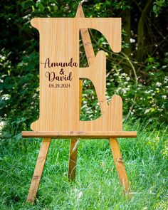 a wooden easel with the words amanda and david on it in front of some grass