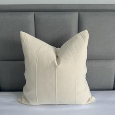 a white pillow sitting on top of a bed next to a gray headboard and night stand