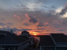 the sun is setting behind some houses