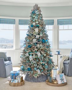 a decorated christmas tree in a living room with blue and silver ornaments on the top