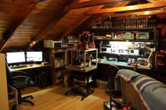 an attic office with two computer screens and lots of clutter