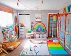 a child's play room with toys and rainbow rugs on the floor in front of windows