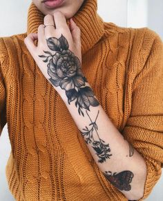 a woman with a flower tattoo on her arm holding a cell phone to her ear