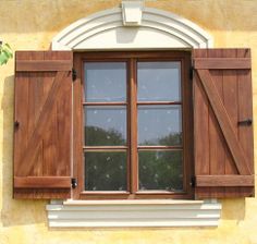 an open window with wooden shutters and white trim