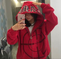 a woman taking a selfie in a mirror wearing a red hoodie with the word love on it