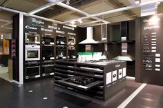 a large kitchen with black cabinets and white counter tops in a showroom or office