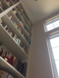 a bookshelf filled with lots of books next to a window