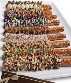 a white plate topped with lots of candy covered pretzels and crackers next to a chocolate bar