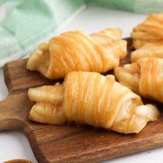 croissants sitting on a cutting board next to a bowl of dipping sauce