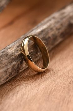 a gold wedding ring sitting on top of a piece of wood